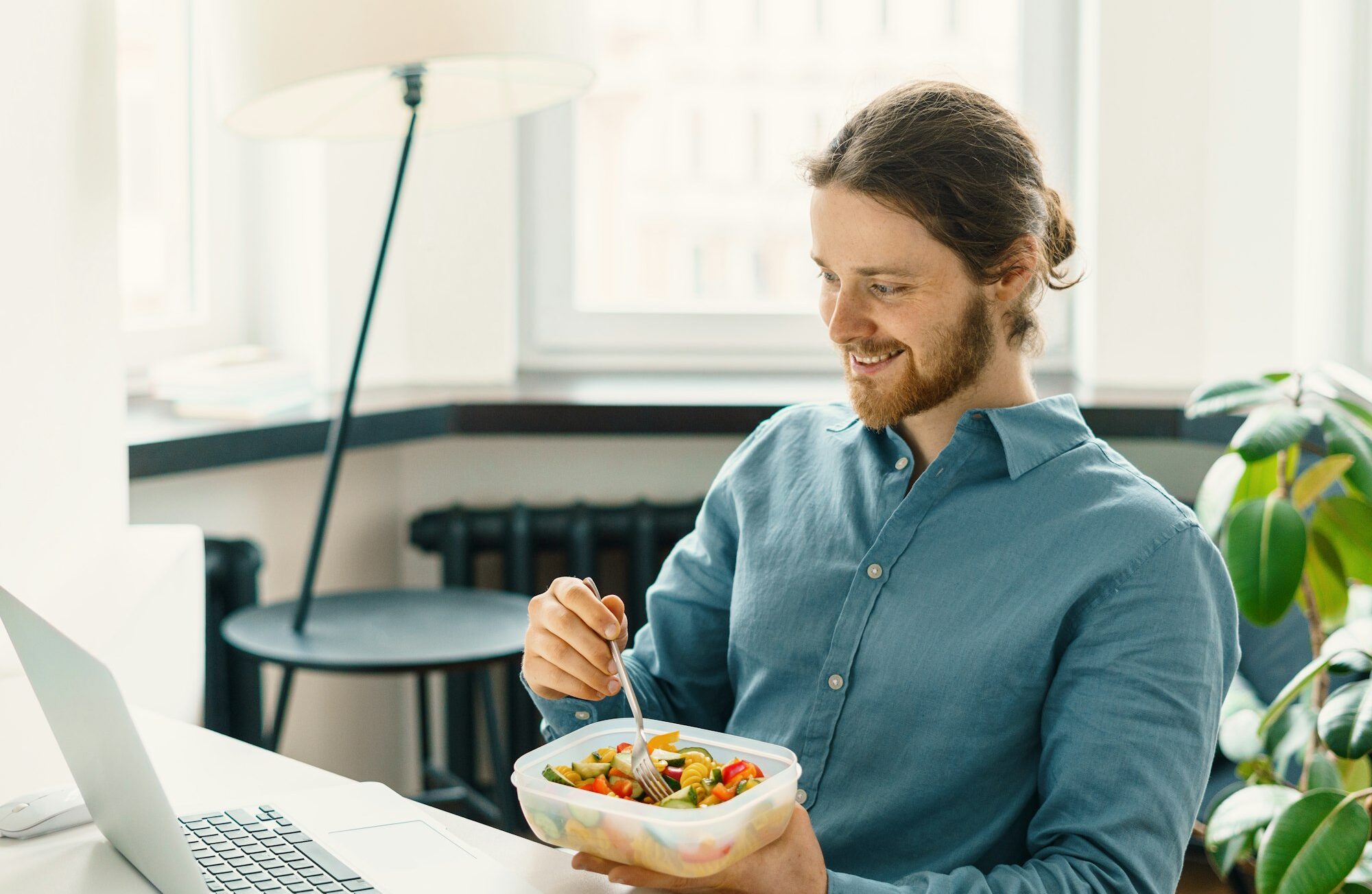 Sitisfied male employee eating vegetarian food at work